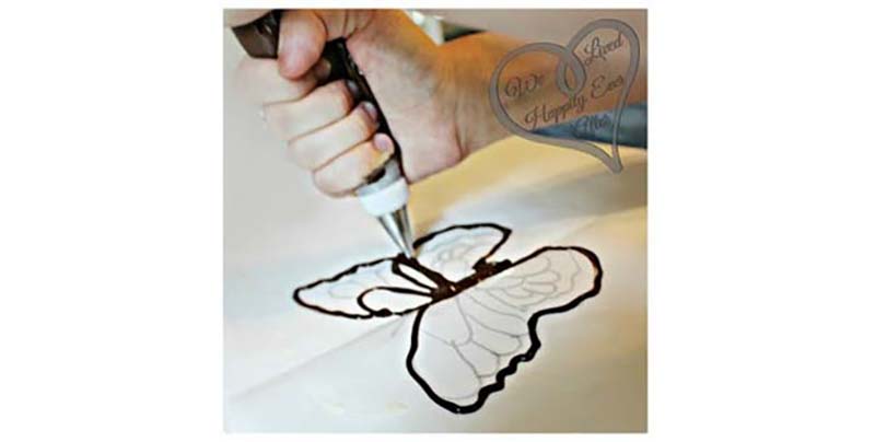 Use a tiny bit of butter to make your wax paper slick. Fold your paper in half to create a crease. Turn it over so the permanent marker side is facing down. Then trace your design on the paper with an icing or ziplock bag.
