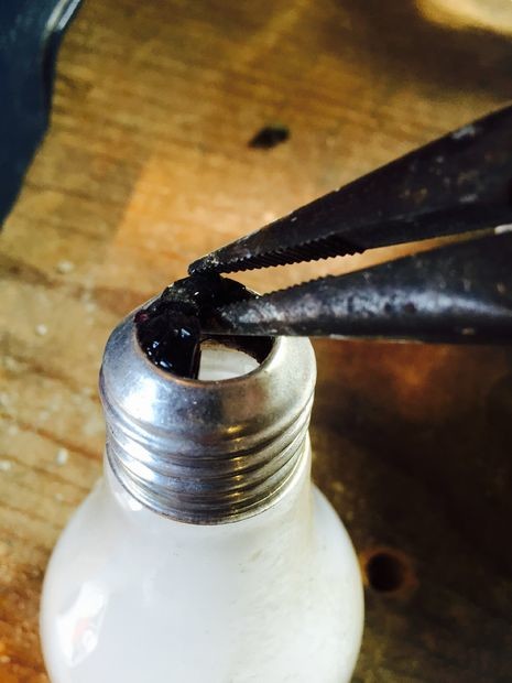 Begin by removing the insides of the lightbulb with a small pair of pliers.
