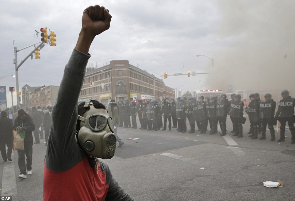'War zone': A rioter wearing a gas mask punches his fist in the air as the streets  fill with smoke while police attempt to restore order