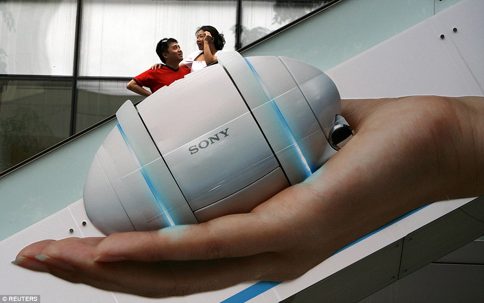 Smart advertising: A couple appear tiny thanks to a giant ad on an escalator at a shopping centre in Singapore's Orchard Road district in January 2009