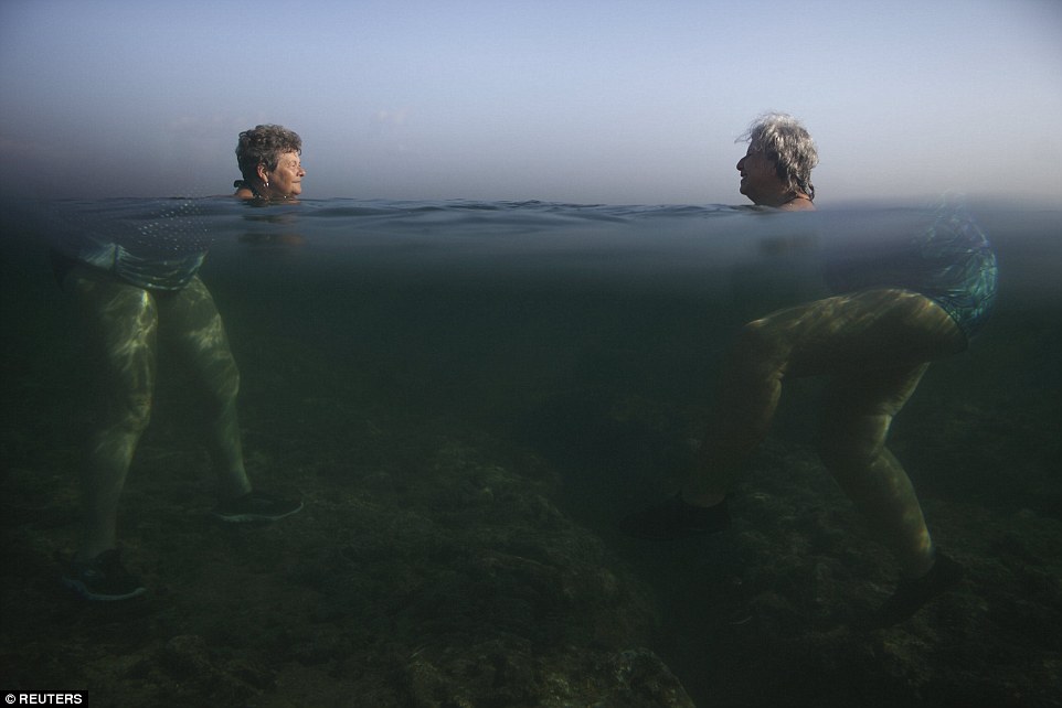 Larger than life: The wonder of science makes these women appear larger than they are as they enjoy a swim in the sea in Havana, Cuba, in April this year