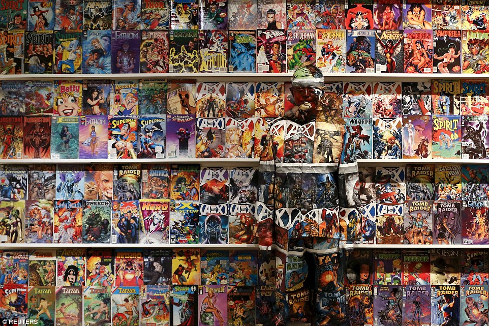 Now you see him: Chinese artist Liu Bolin blends himself into the background in front of a shelf lined with comic books as part of a series of performances in Caracas, Venezuela, in November 2013