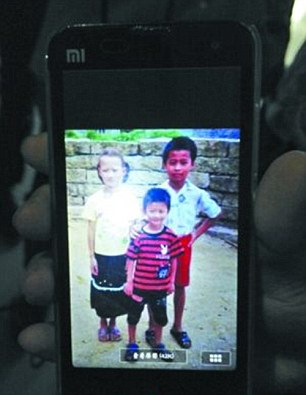 Zheng's birthparents show a photo of him with friends taken before he was abducted. Zheng is the tallest in the picture