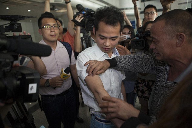 This is the amazing scene where He Zhirong, right, checks the arm of his son He Qingtang, centre, who was abducted 18 years ago at the age of four and given the name Zheng by his new adoptive family 