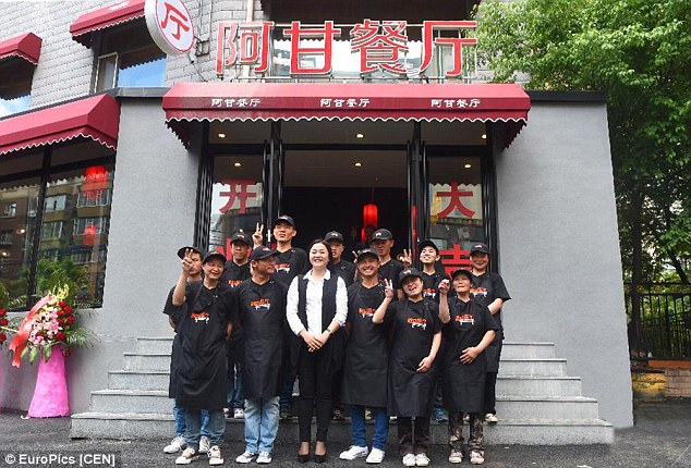 Founder of the restaurant, Hu Yanping (middle), is taking a picture in front of the restaurant with all mentally impaired staff, whom she refers to as 'my children'