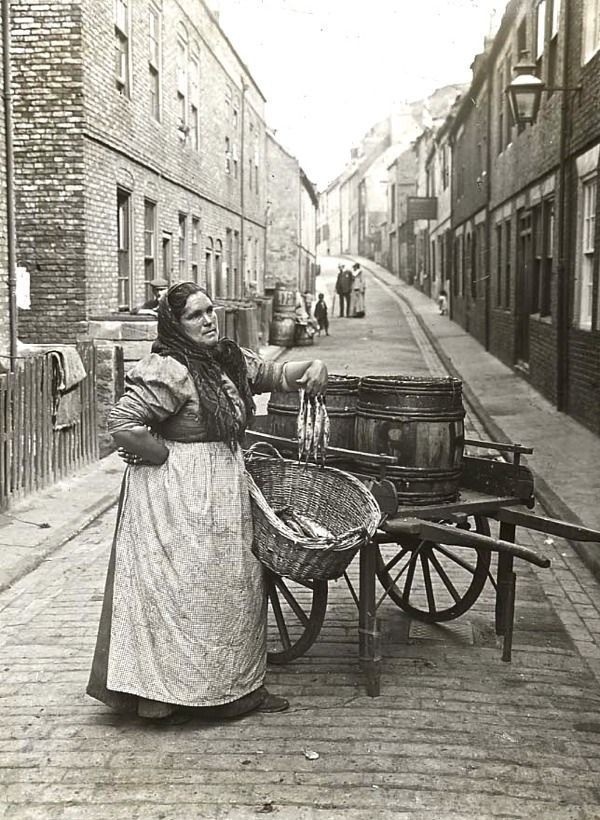 Woman selling fish from a barrel on the streets of London, 1910.