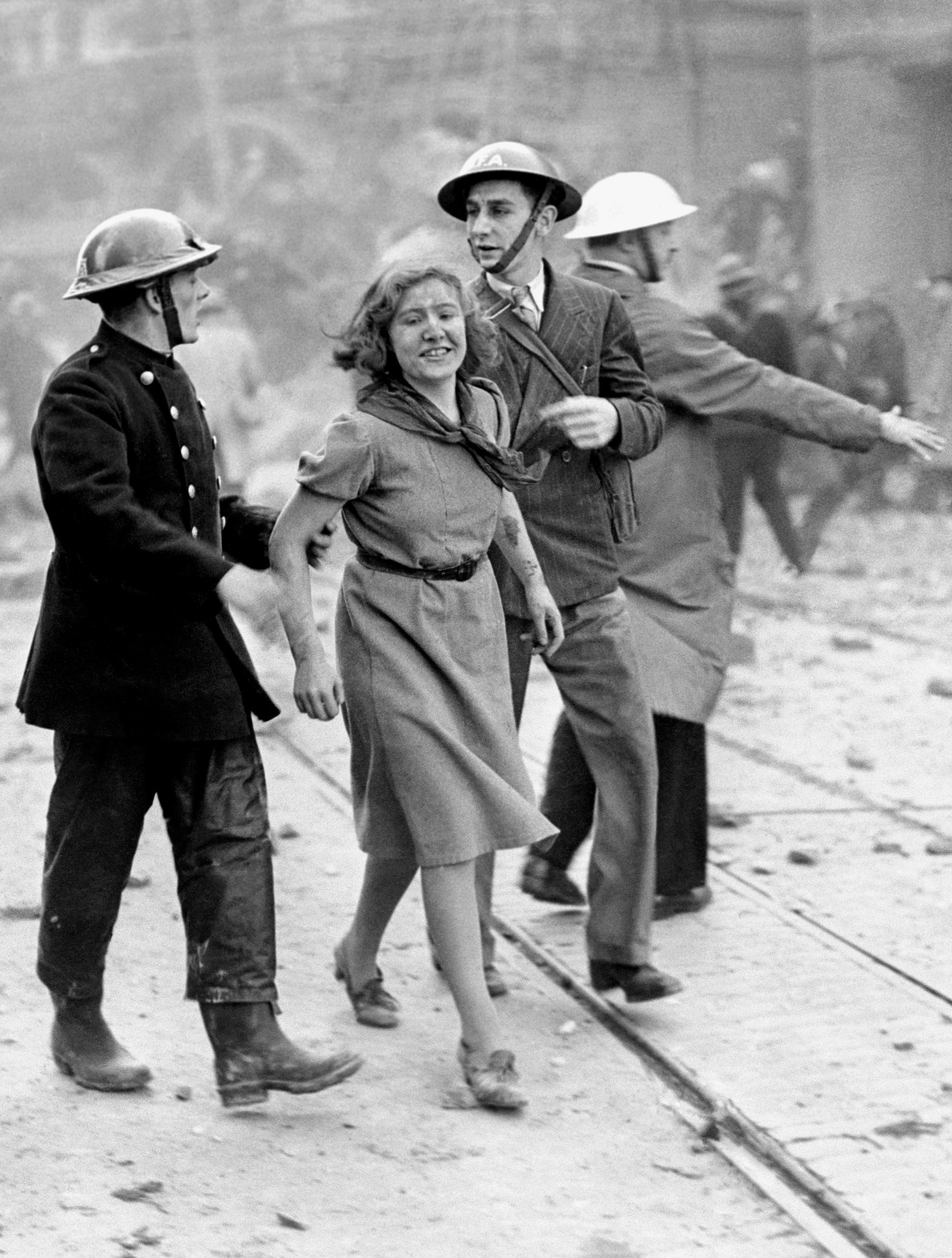 A girl  being assisted in London, after being rescued from a damaged building caused by a German bombing raid. Clearly, nothing could stop her from smiling.