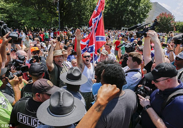 Rally: A Confederacy supporter  raises the Nazi salute while surrounded by police officers and cameras at the rally on Saturday outside South Carolina statehouse