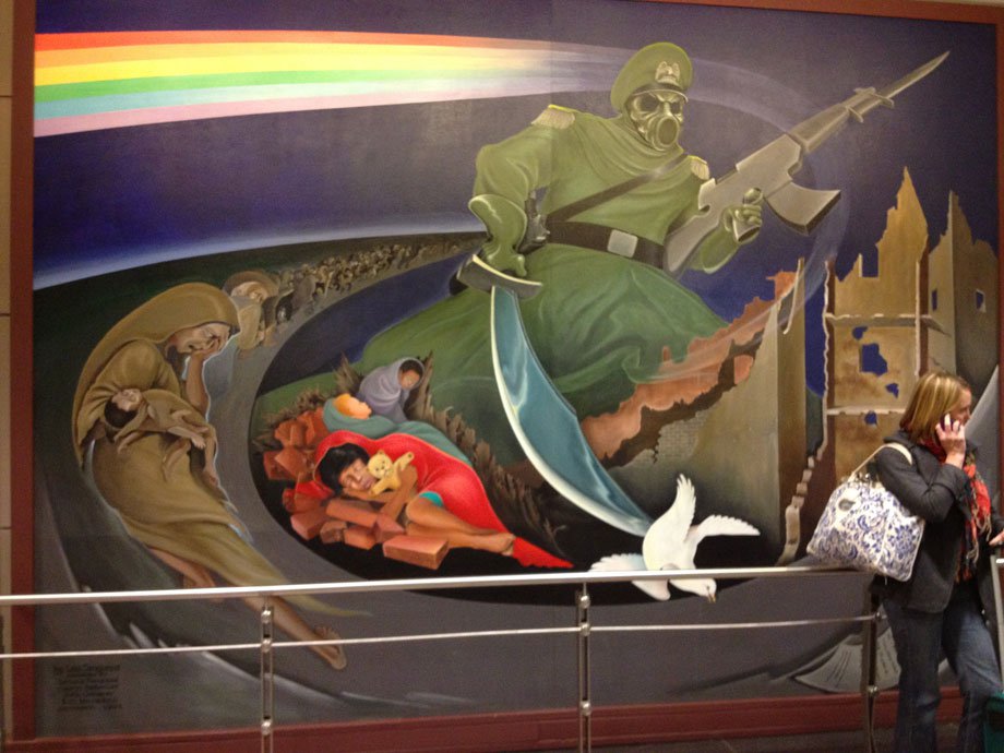 The murals are fairly shocking. Here we have efugees living in a basement and the Lord of Death, brandishing an AK-47, killing the dove of peace.<br /><br /><br /><br /><br /><br /><br /><br /><br /><br /><br /><br /><br /><br /><br /><br /><br /><br />
Gray waves pulse from the figure, the waves pulse outward, killing everybody in its path. The figure wears a gas mask implying the gray waves, the instrument of death in this case,  is a biological weapon.