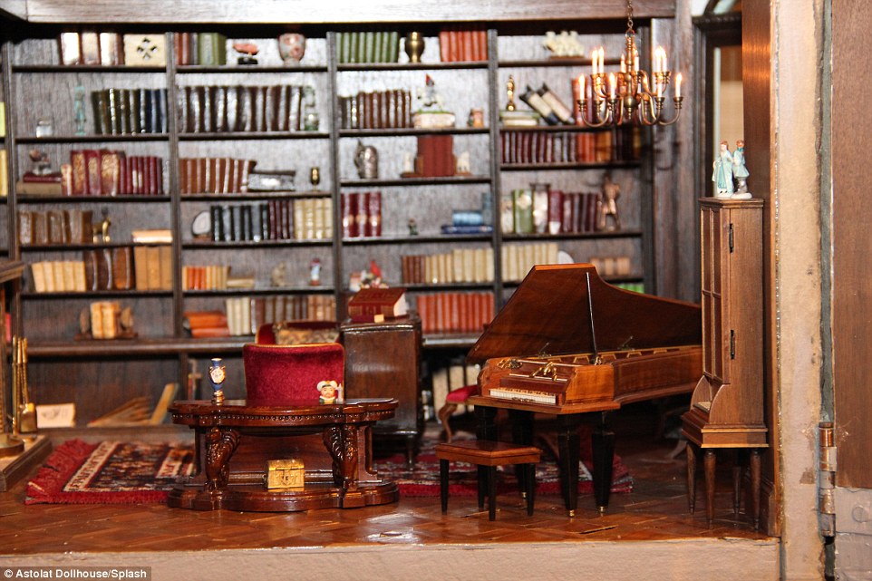 A tiny grand piano is seen in one of the 29 rooms in the dollhouse in this photo along with dozens of mini books