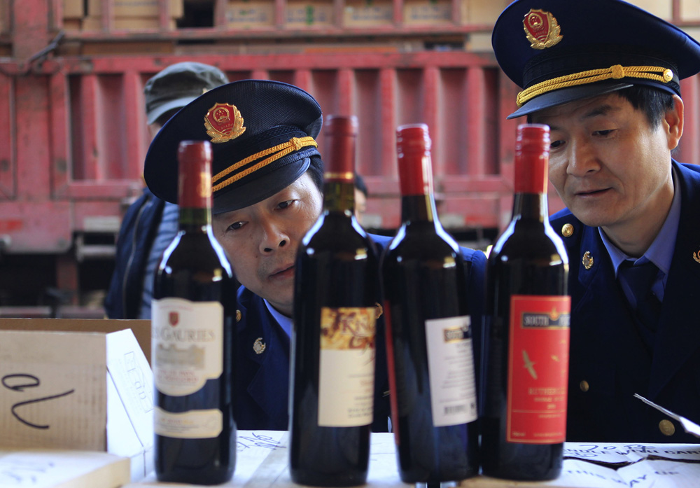 Police officers check bottles of confiscated fake wines before destroying them in Xi'an
