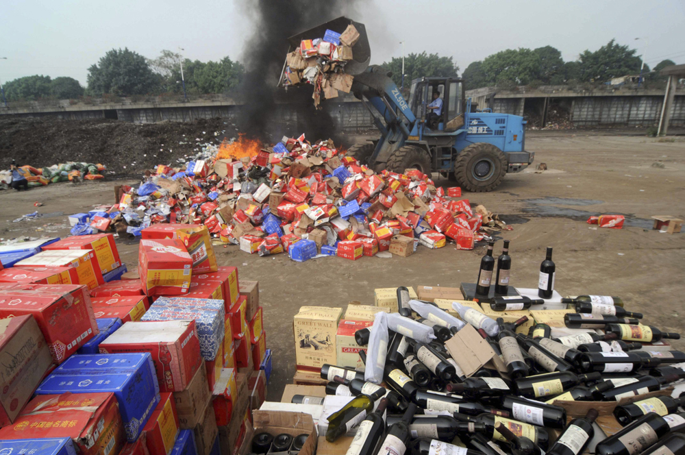 Confiscated bottles of fake wines are destroyed by the police in Nanning