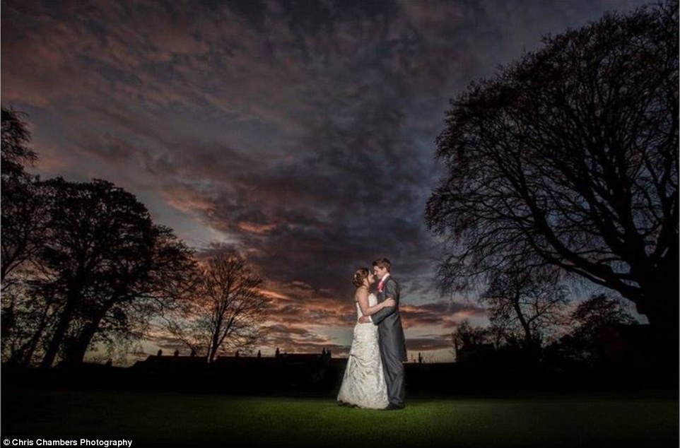 What the couple put in their wedding album: This wedding snap shows the bride and groom embracing beneath a moody sky 