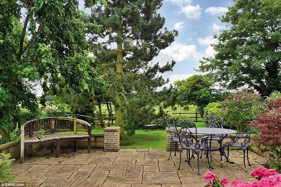 Pleasant surroundings: Outside in the peaceful churchyard of the Lincolnshire home are landscaped grounds and a raised patio area