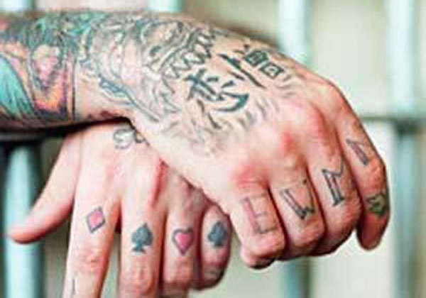 EWMN

These letters stand for ‘Evil, Wicked, Mean, Nasty.’ Having no particular affiliation with any gang, they simply represent the general disposition of some prison inmates. Typically found on the knuckles, these types of tattoos were popularized in 1955 by Robert Mitchum in ‘The Night of the Hunter.’ His sociopathic preacher character had the words ‘love’ and ‘hate’ tattooed on the knuckles of each hand, which has brought about other variants such as ‘Rock/Roll’ and ‘Stay/Down.’
