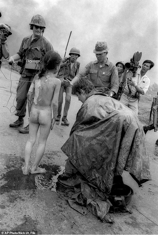 In this June 8, 1972 photo, television crews including ITN reporter Christopher Wain and South Vietnamese troops surround 9-year-old Kim Phuc on Route 1 near Trang Bang after a South Vietnamese plane targeting suspected Viet Cong positions accidentally dropped its flaming napalm on the civilian village.