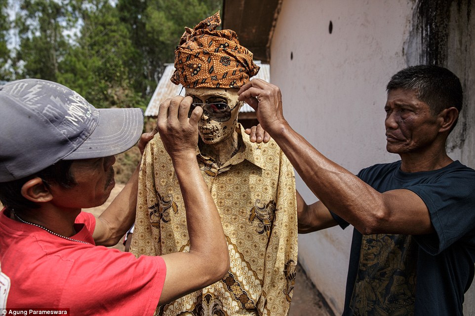 Dressing up: The Tiranda family put sunglasses on the mummy of Yohanes Tampang (centre) during the Ma'Nene ritual in Pangala Village, Toraja, held every three years