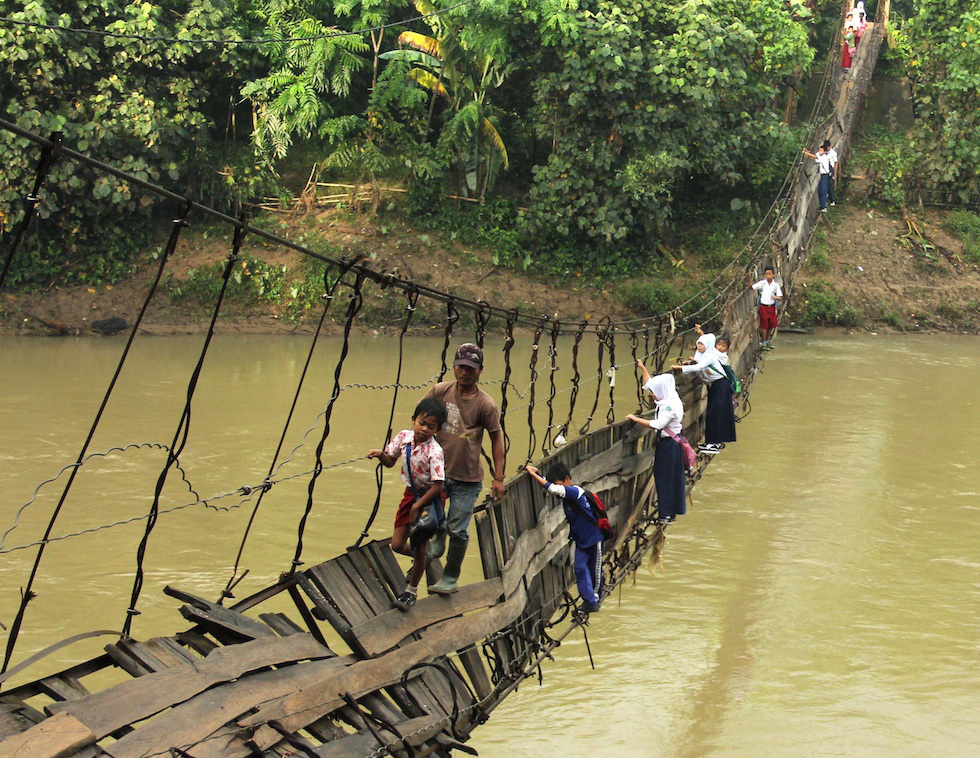 Kids have to crossed a damaged suspension bridge in Lebak, Indonesia to get to class. At least some of the parents are there to help out.