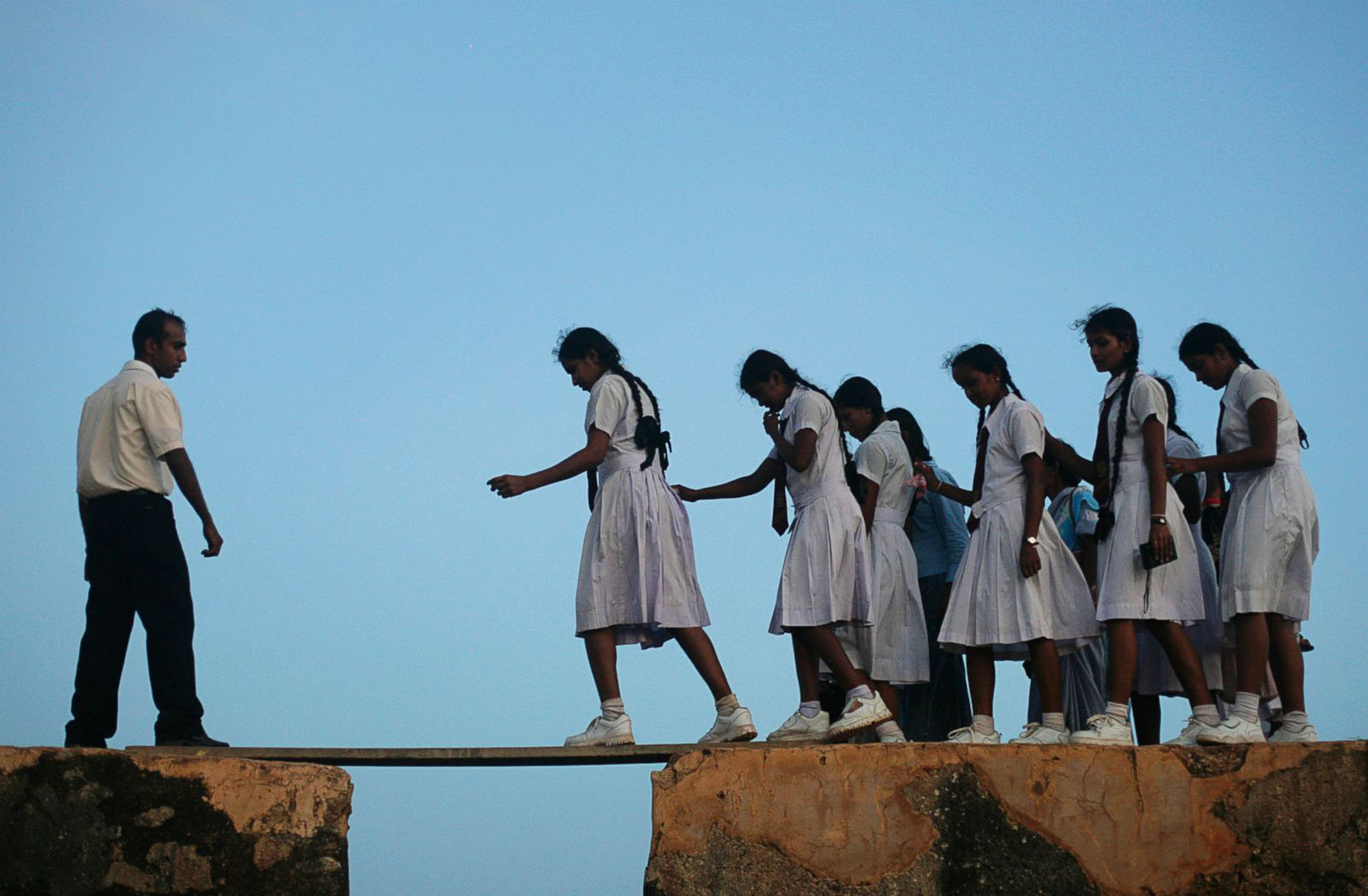 School girls walk across a plank on the wall of a 16th century fort in Sri Lanka.