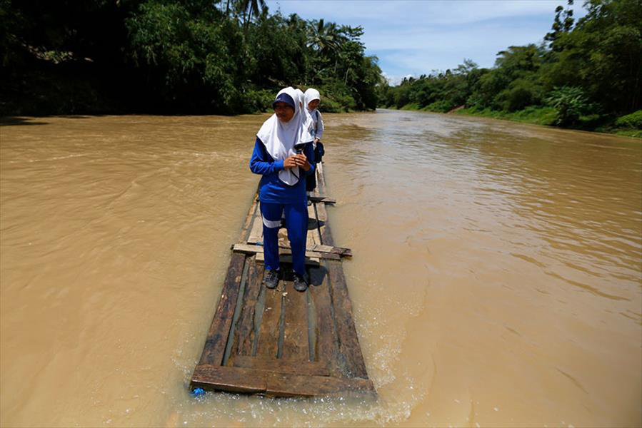 Kids must cross the Ciherang River on  makeshift bamboo raft in Cilangkap Village, Indonesia.