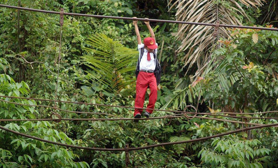 Try not to be late while having to walk the tightrope 30 feet above a river in Padang, Sumatra, Indonesia.