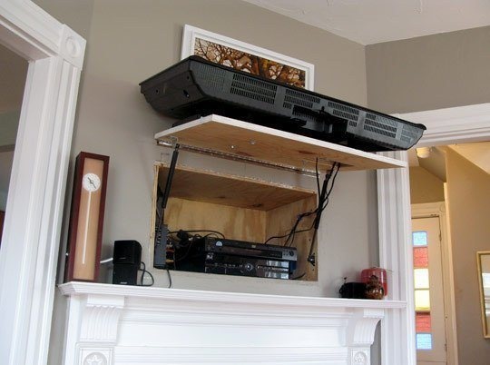 Mount your tv over a board that is hinged with gas springs to create a secret compartment behind your tv.