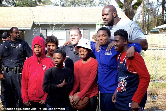 Special guest: Basketball legend Shaquille O'Neal surprised the kids who play ball in a Gainesville neighborhood - he showed up as 'backup' for a pick up game with Officer Bobby White (middle)