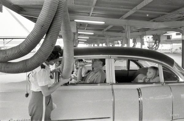 Getting cooled air piped into the car while enjoying a meal at a drive-in restaurant. Houston, Texas. 1957