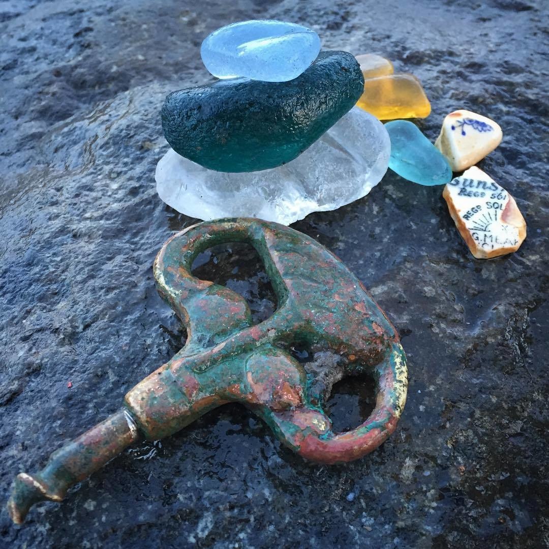 Sea glass, key, and bits of pottery made their way onto a rock. 