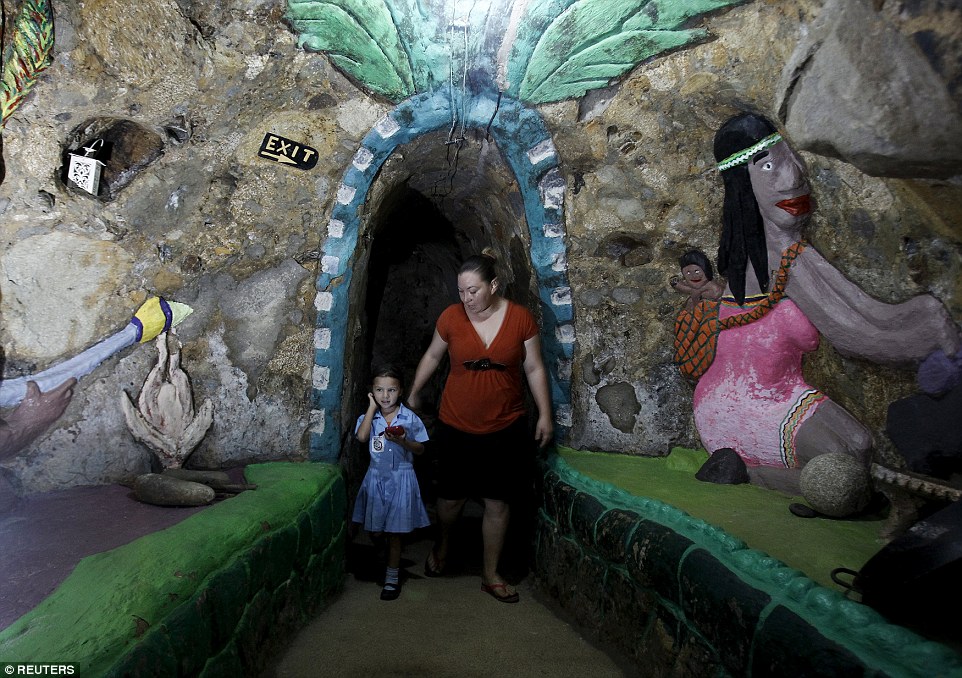 Lidieth Barrantes and her daughter walk through one of their house's hallways, which is brought to life by a painting of a woman and baby