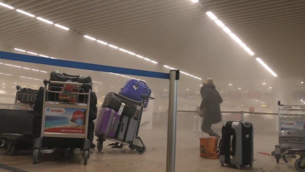 In this photo provided by Ralph Usbeck an unidentified traveller runs in a smoke filled terminal at Brussels Airport, in Brussels after explosions Tuesday, March 22, 2016. Authorities locked down the Belgian capital on Tuesday after explosions rocked the Brussels airport and subway system, killing a number of people and injuring many more. Belgium raised its terror alert to its highest level, diverting arriving planes and trains and ordering people to stay where they were. Airports across Europe tightened security. (Ralph Usbeck via AP)