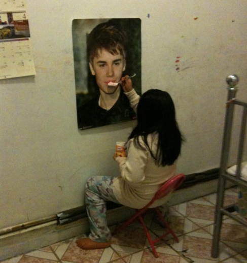 Kids today: This girl is literally feeding yogurt to a poster.