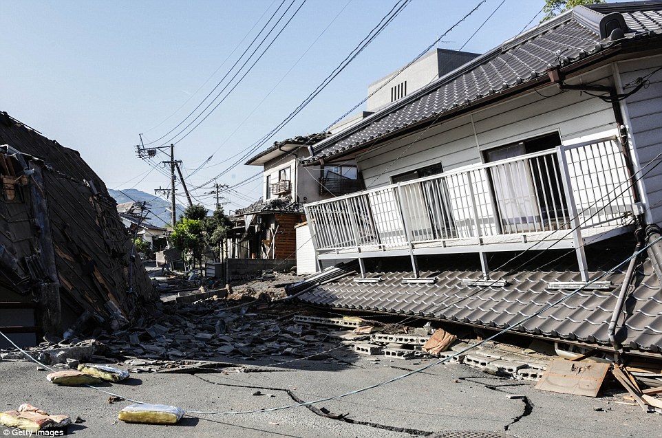 Devastation: A house collapsed in on itself, totally destroying the entire ground floor. The street is strewn with debris after the quake  