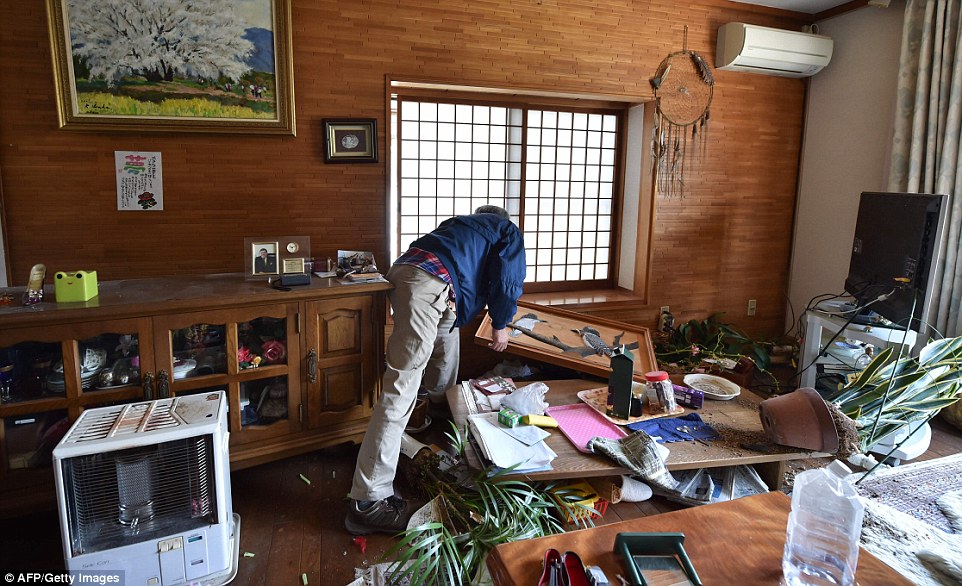 Wrecked: Resident Nobuyuki Morita cleans up a room damaged by an earthquake in his house in the town of Mashiki