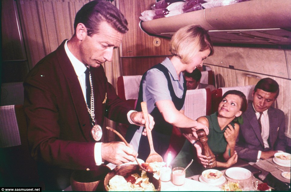 In this photo taken in the 60s, an air stewardess is offering pepper to her guest while a sommelier, wearing a silver tasting cup, is ladling out the salad 