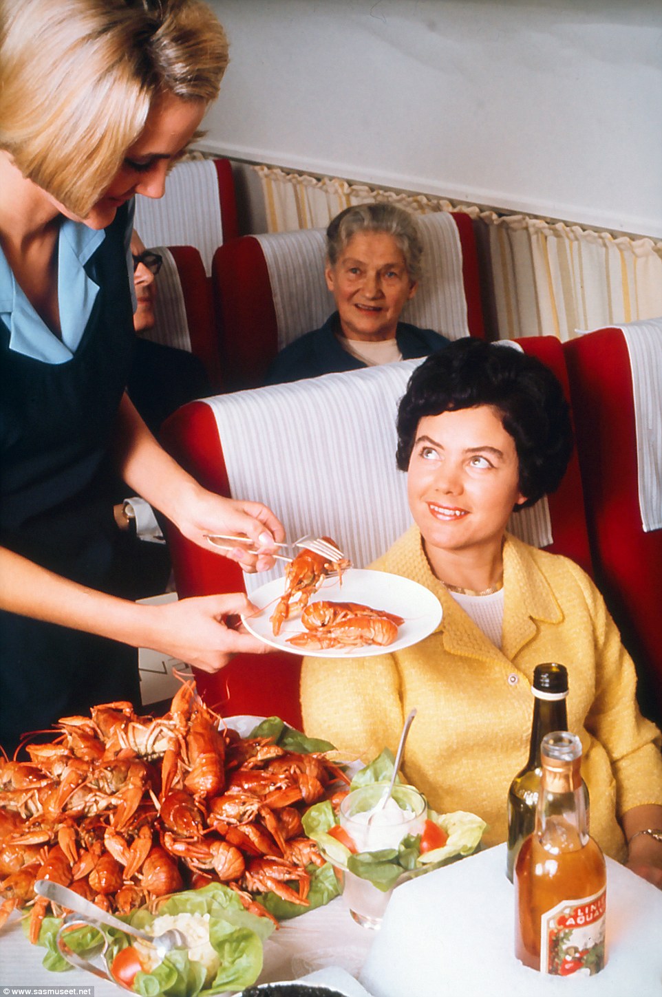 In this undated photograph, a passenger is being served fresh Norwegian lobsters with their shell still on. Two aperitifs are set on ice next to the rest of the shell fish on the trolley