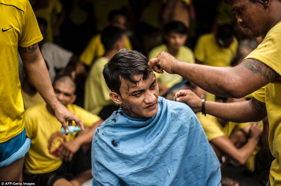 One inmate gets his hair cut by another inmate inside the crowded Quezon City Jail as others watch on 