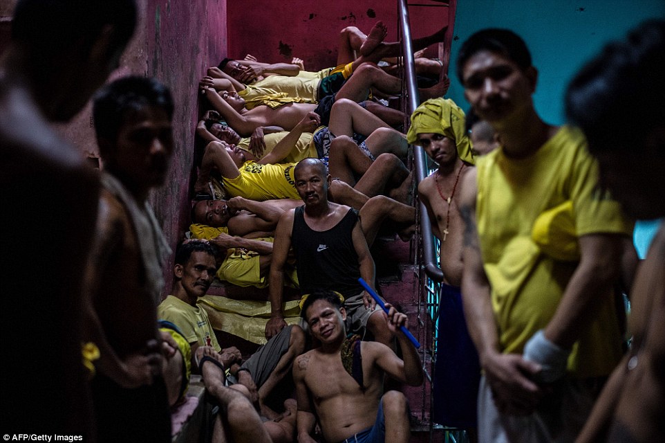 Inmates settle in for the night on the steps of a ladder inside the Quezon City jail.  There is a relentless and constant battle for space
