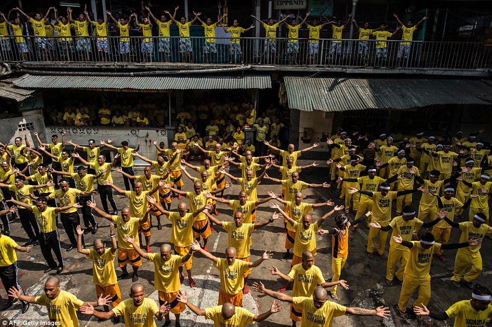 Wearing their regulation yellow shirts, prisoners are pictured participate in group dancing contests, taking over the concrete space and the walkway above