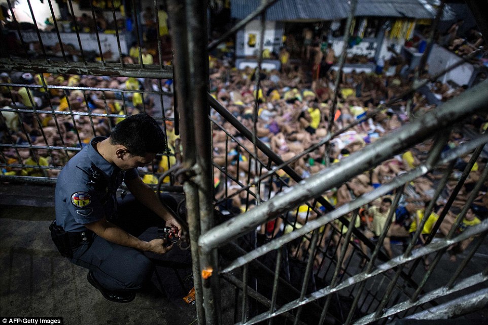 A prison guard locks a gate inside the Quezon City jail as the men camp down for the night on the floor of the overcrowded prison