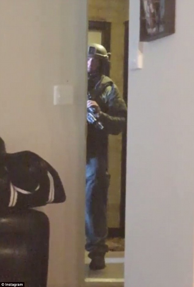The standoff lasted about six hours, during which Gaines posted one video of a policeman in tactical gear standing in her doorway (pictured), and another clip shows her son saying police are trying to kill them