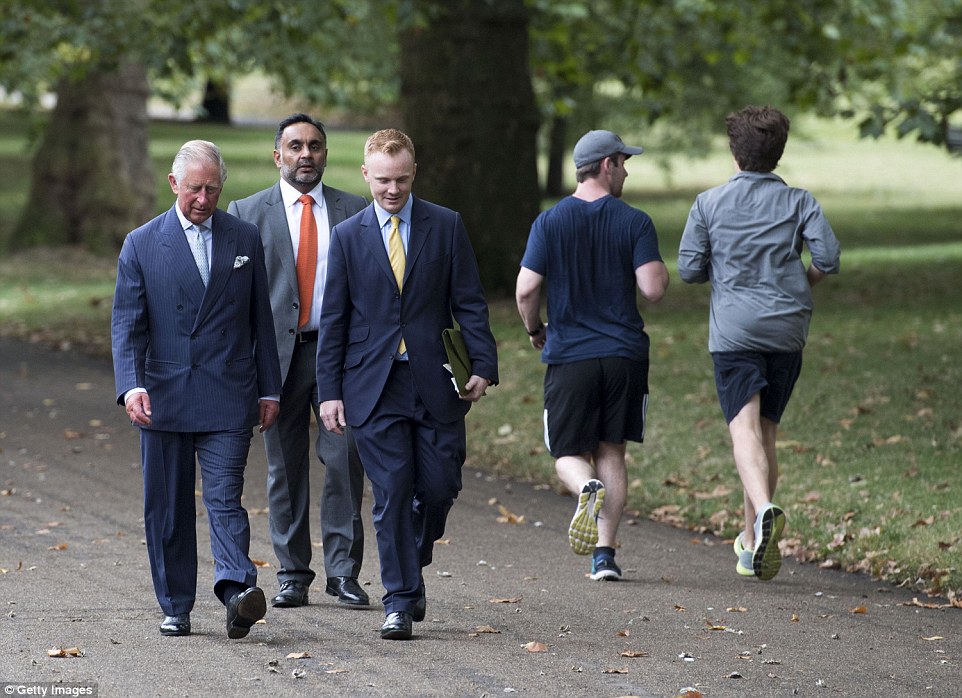 Out for a run: Two joggers breeze straight past Prince Charles (left) as he walks through Green Park in London today