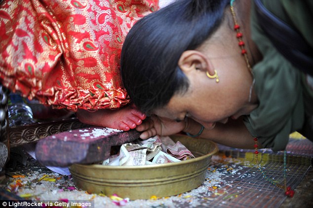 Devotee honours Living Goddess by touching her feet and placing money in a pot. In 2008 Nepal's Supreme Court overruled a petition to end the practice, citing its cultural value although some activists claim the tradition is child labor.