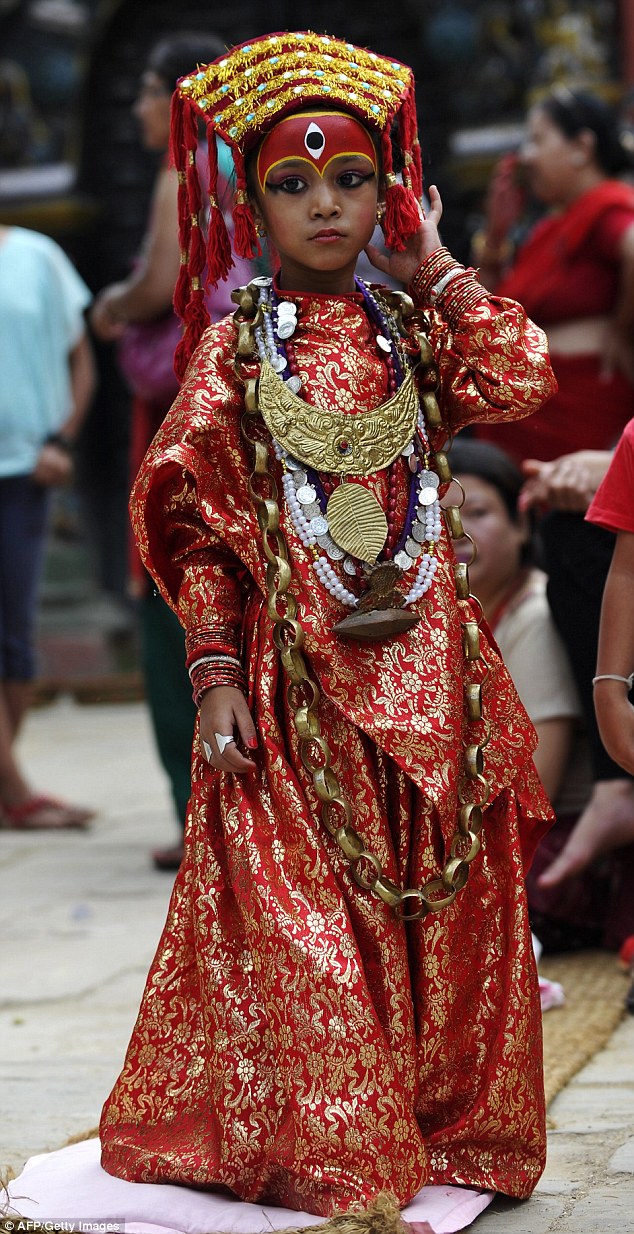 A Nepalese girl dressed as a Kumari, or living goddess, looks on as she takes part in Kumari Puja rituals at the Hanuman Dhoka in Durbar Square in Kathmandu