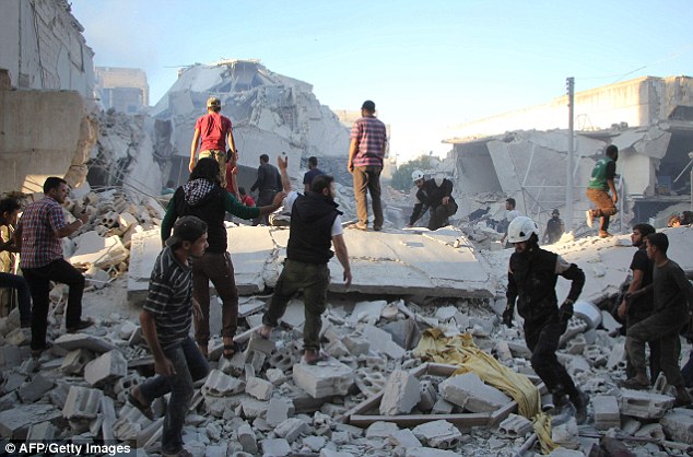 Syrian men search for people under the rubble of destroyed buildings after at least five air strikes hit various areas in the city of Idlib on Thursday