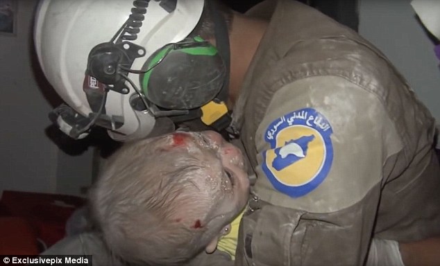 Saved: Syrian White helmet volunteer Abu Kifah and his colleagues were able rescue a 30-day-old baby from under the rubble in the city of Idlib on Thursday