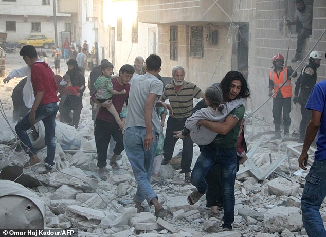 Frantic: Syrian men carry injured people amid the rubble of destroyed buildings following an air strike on the rebel-held northwestern city of Idlib on Thursday
