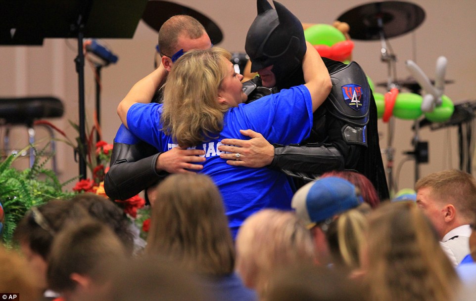 John Buckman, dressed as Batman, hugs the aunt of Jacob Hall, Rebecca Hunnicut, after speaking during the funeral service