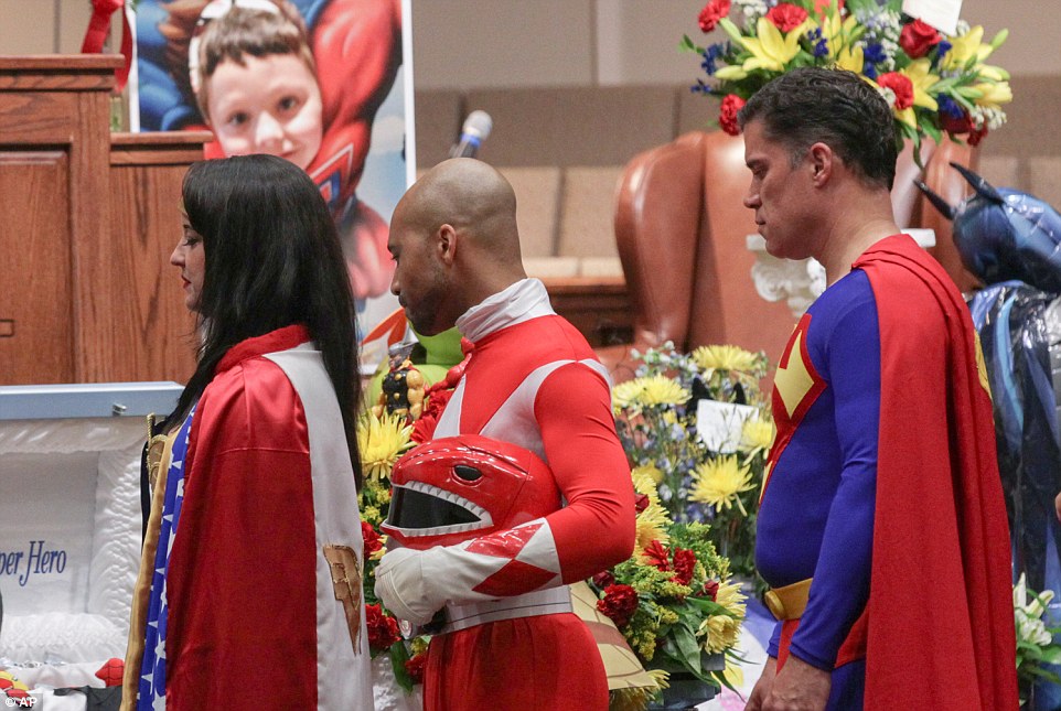 Katie Olvera (left) dressed as Wonder Woman, Aaron Sloan (center), dressed as a Power Ranger, and John Suber (right) dressed as Superman at a wake service for Jacob on Tuesday