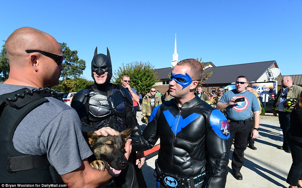 Men dressed as superheroes speak to a police officer outside the funeral for Jacob Hall on Wednesday